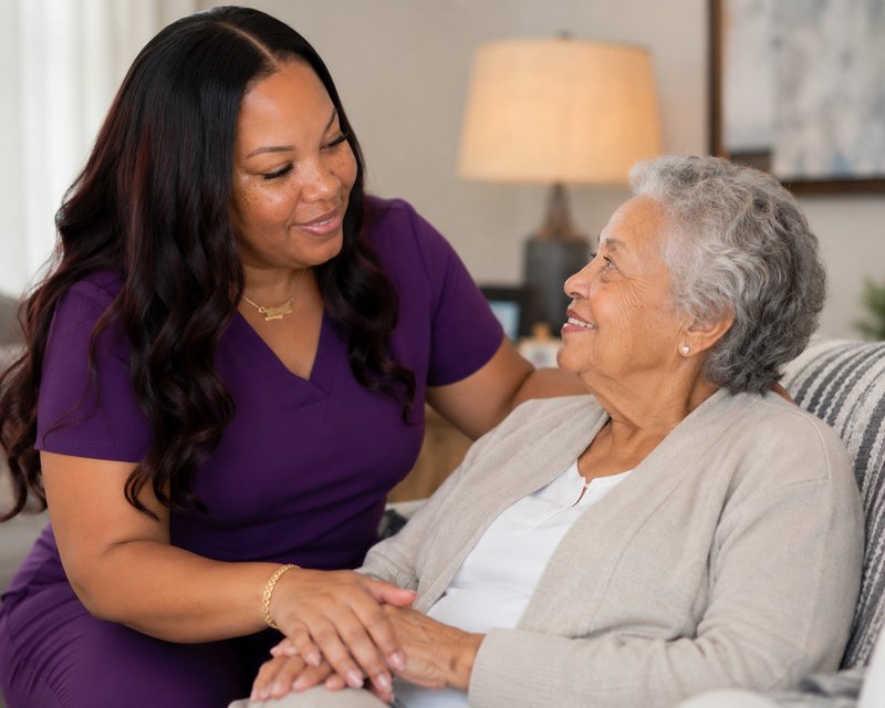 Shanika Perkins sitting with a client at home, holding her hand